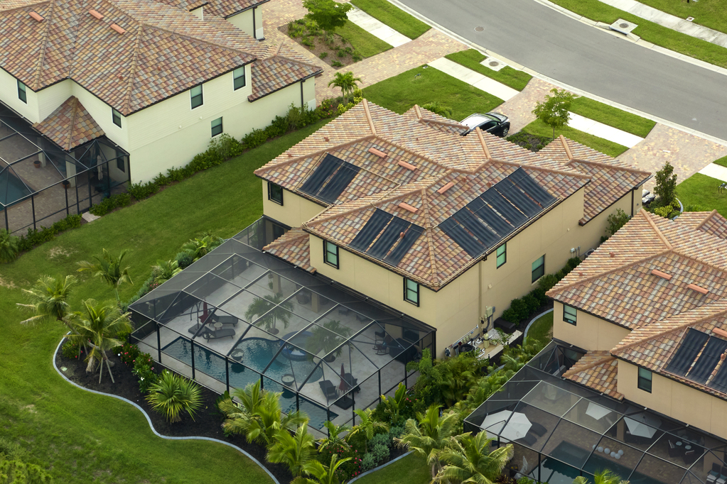 Aerial view of expensive modern houses with outside swimming pool covered with mosquito mesh on metal frame for insect protection in Florida closed living club